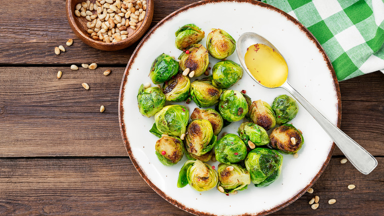 Grilled brussels sprouts with pine nuts on a white plate