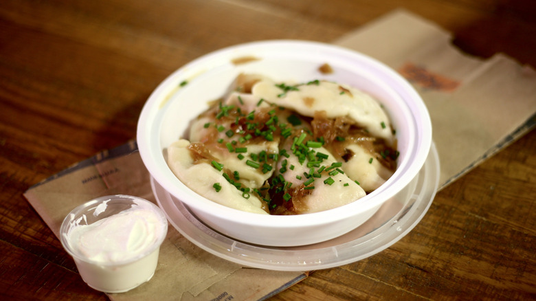 Close-up of pierogi in a takeout container on a wooden table