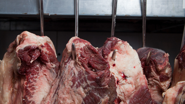 Sides of beef hanging from meat hooks