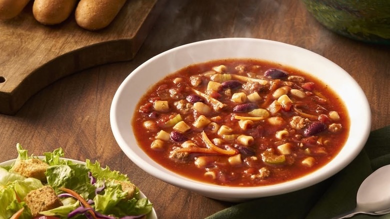 Olive Garden minestrone soup with breadsticks and salad just in view