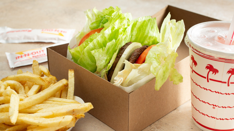 Two protein style burgers in a cardboard box with fries and a drink