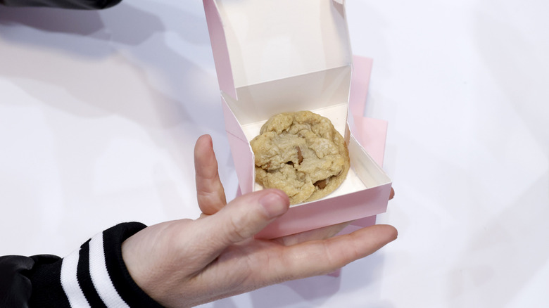 customer holding a boxed Crumbl cookie