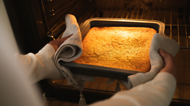 Someone pulls a dense cake out of an oven