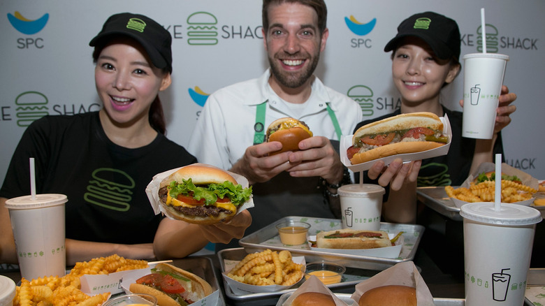Mark Rosati, culinary director of Shake Shack showing the chain's food at an event with 2 workers
