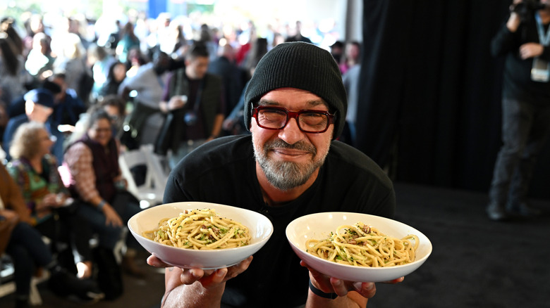Chef Michael Symon holding plates of pasta.
