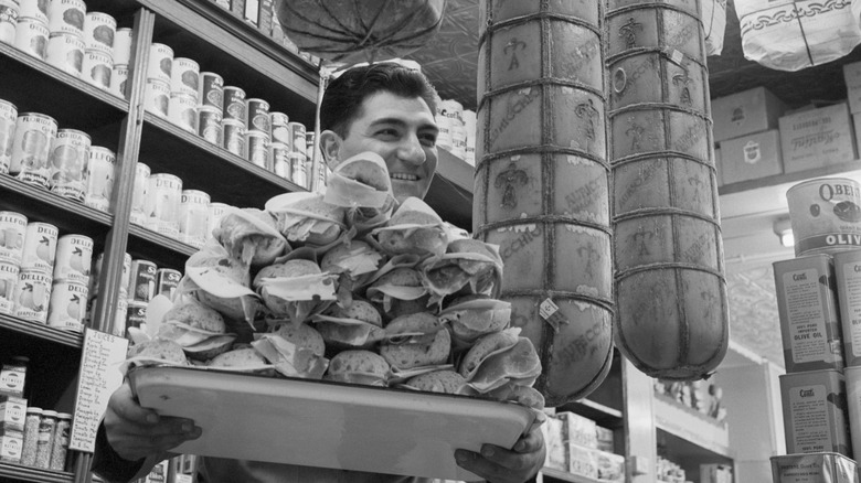 Man carrying a tray of hero subs at a deli in 1959