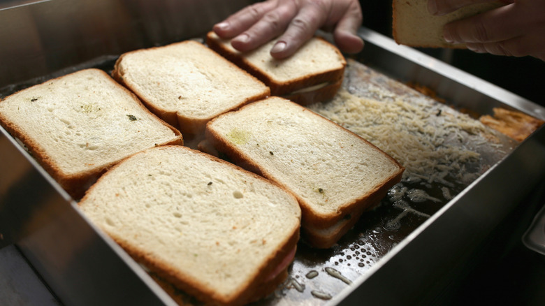 Someone preparing multiple grilled cheese sandwiches on a flat top