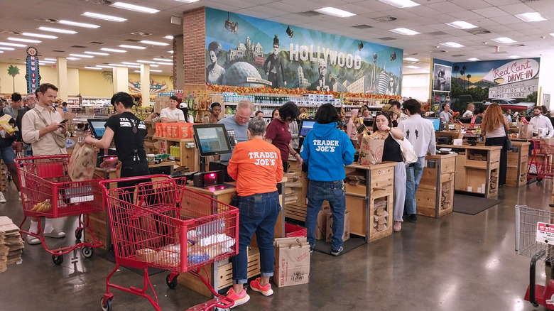Interior shot of a Trader Joe's check out area filled with people, workers, and full carts