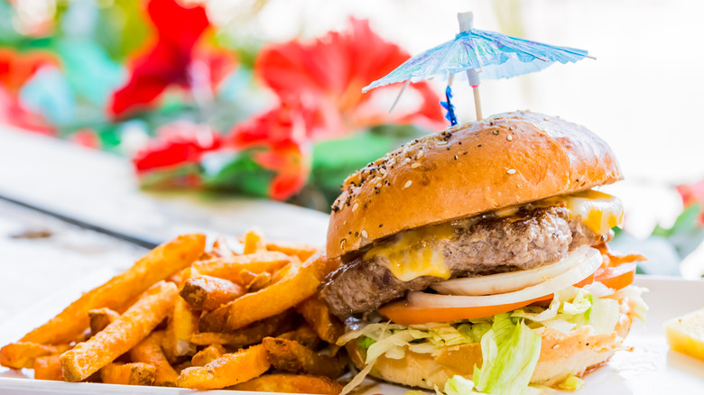 Fries and a cheeseburger with cocktail umbrella and bright sunshiney background