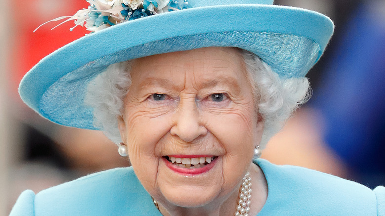 Queen Elizabeth smiling in blue hat