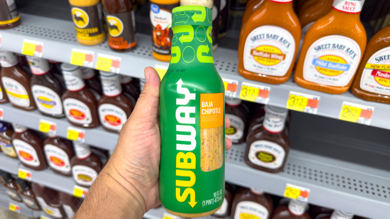 Hand holding Subway Baja Chipotle sauce in supermarket