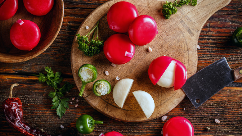 Scattered Babybel cheeses, herbs, peppers on cutting board