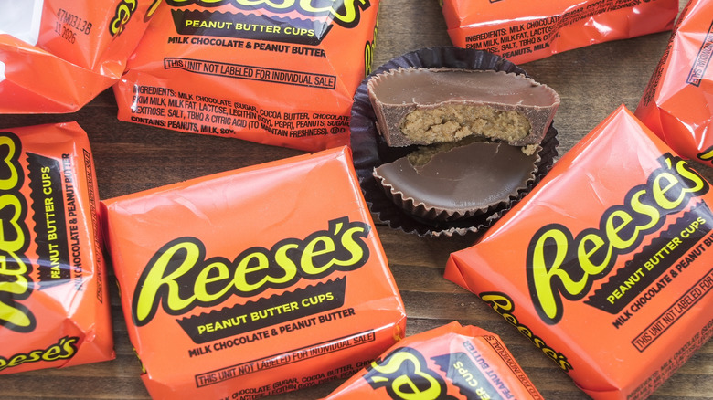 Packages of Reese's Peanut Butter Cups, with one cup out of the package and broken in half