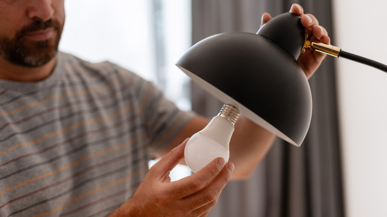 Man installing light bulb into lamp