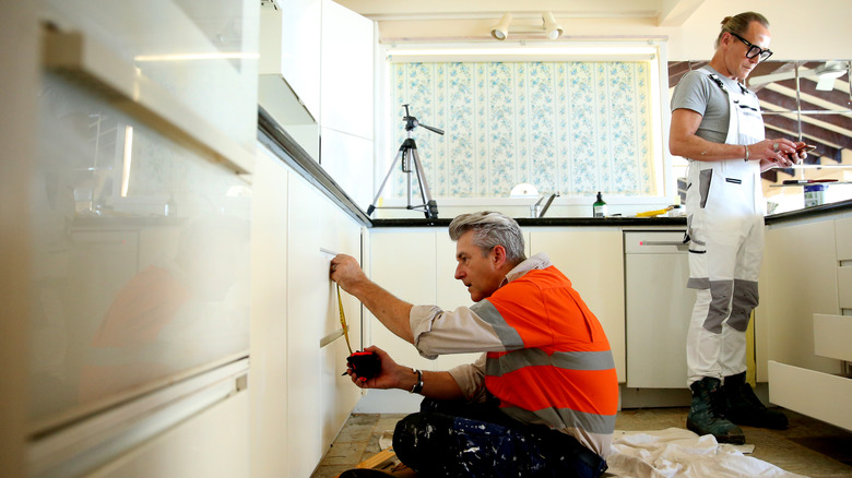 Contractors installing cabinetry in kitchen