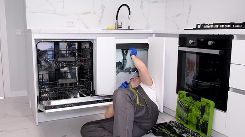 Plumber working under kitchen sink