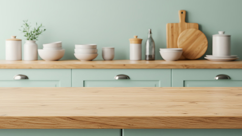 Kitchen with mint green walls and cabinets and wood counters lined with dishes