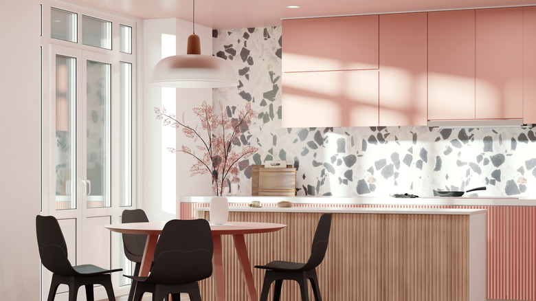 Kitchen with pink cabinets and gray and white patterned accent wall