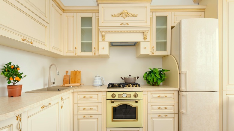 Cream colored kitchen with antique style cabinets and white fridge