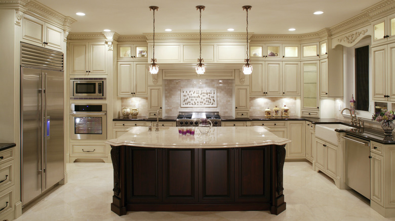 A luxury kitchen featuring layered lighting design from hanging, recessed, and under cabinet lights