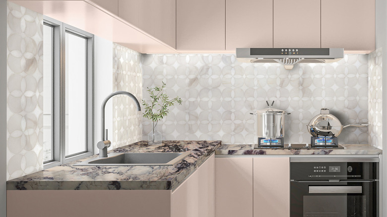 A luxury kitchen with blush pink cabinets and breccia violetta marble counters.