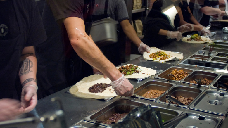 The ordering line at Chipotle, employees creating burritos and bowls
