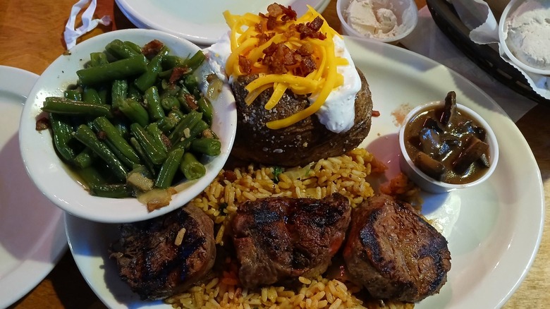 Texas Roadhouse filet medallions over rice with loaded baked potato and green beans