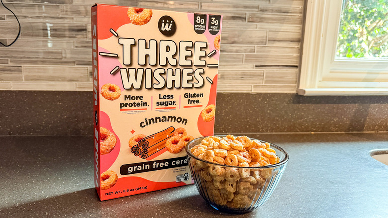 A box and bowl of Three Wishes Cinnamon protein cereal are shown.
