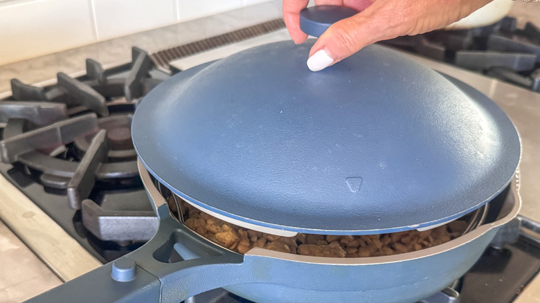 hand covering pan with lid