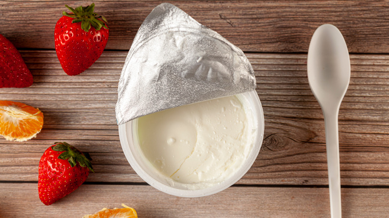 Yogurt pot alongside spoon and fruit