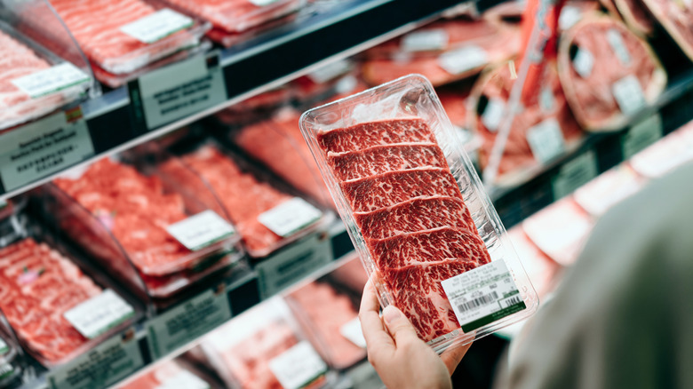 person shopping for steak at the grocery store