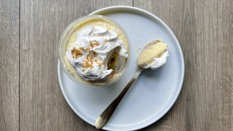 A Coconut Cream Pie Cup from Buc-ee's on a plate with a spoon full of the pudding sitting next to it