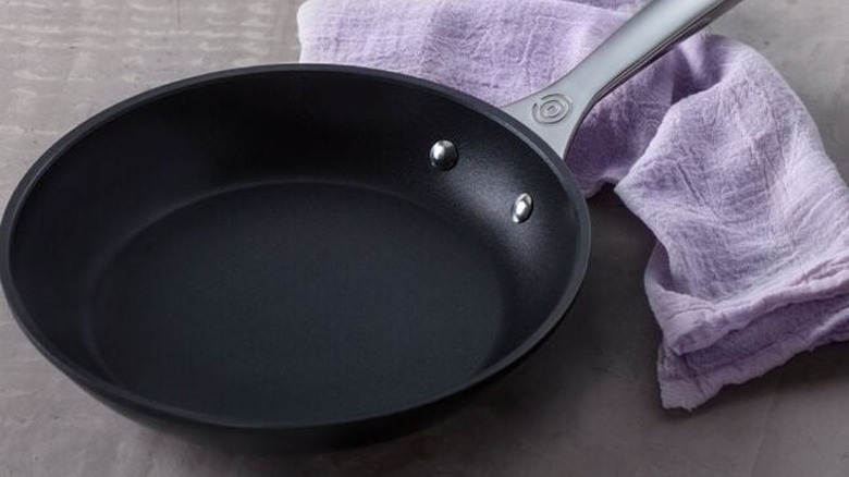 The Le Creuset Toughened Non-stick PRO frying pan on a counter with a lilac tea towel