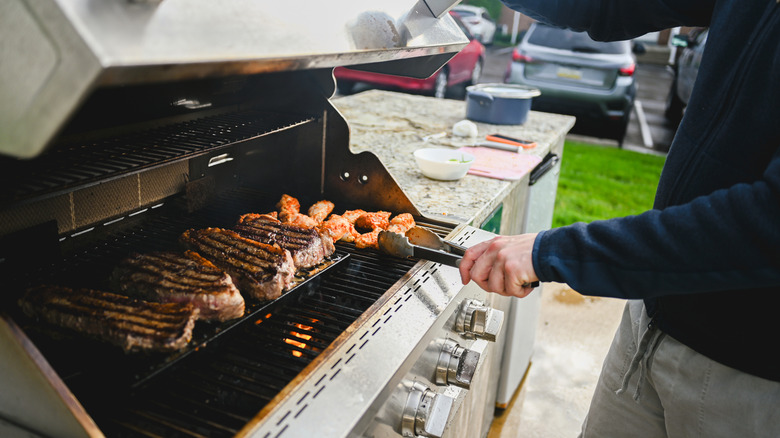 Someone cooking steaks on a gas grill
