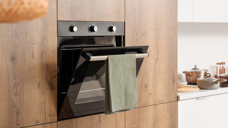 Built-in wall oven against wooden cupboards and white kitchen space