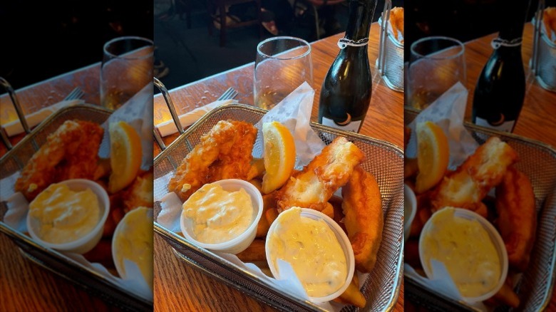 Battered fish in a basket, accompanied by a lemon wedge and two sauces, at the Hanger on the Wharf