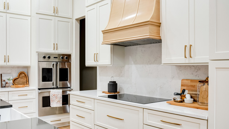 A beautiful kitchen with white cabinets and gold handles.