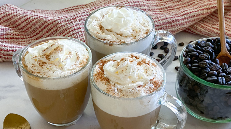 three lattes in clear mugs