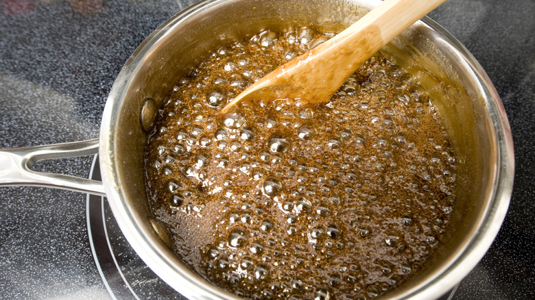 Caramel cooking in a pot on the stove with a wooden spoon