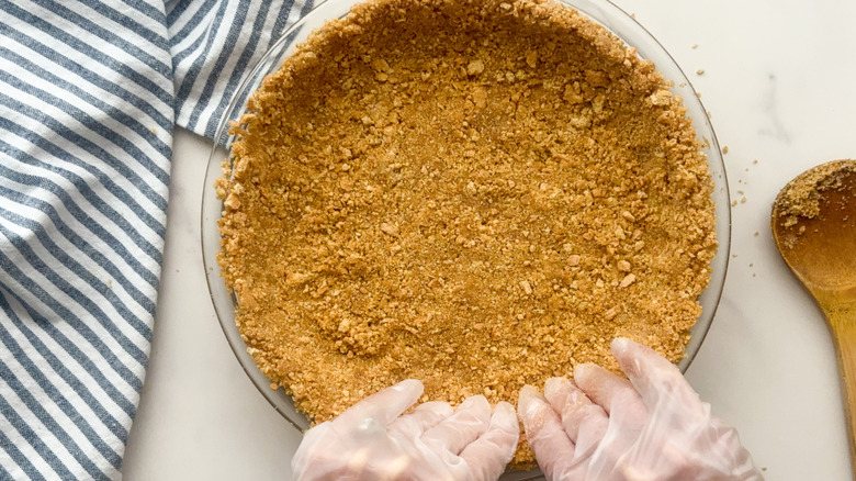 hands pressing crust into pie plate
