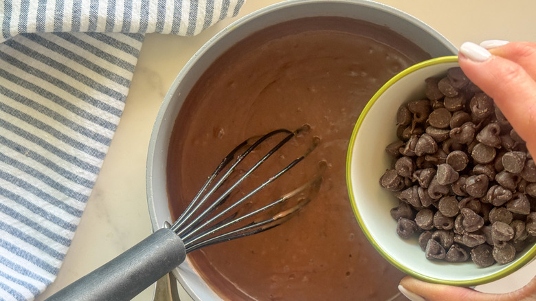 hand adding chocolate chips to pot