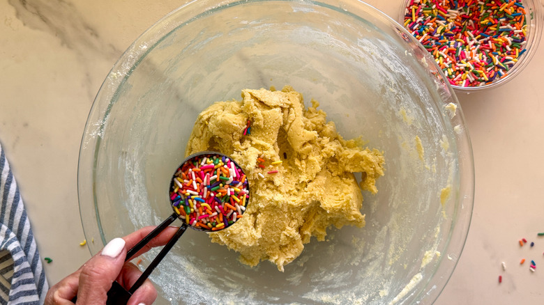 hand adding jimmies to bowl