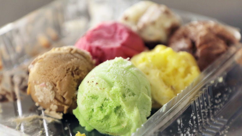 different ice cream flavor scoops sit in a container.