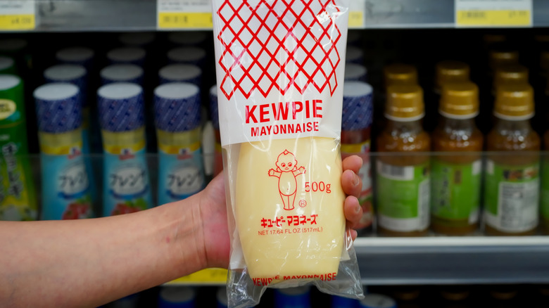 Shopper holding a bottle of Kewpie mayo in a grocery store