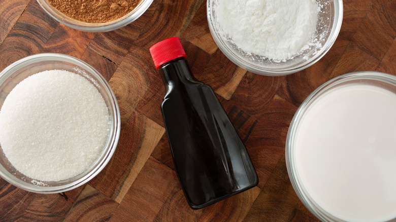 Vanilla extract bottle beside bowls of other baking ingredients