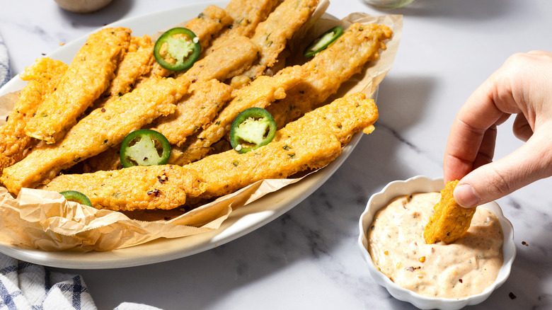 Dipping spicy cheese straw into smoked aioli