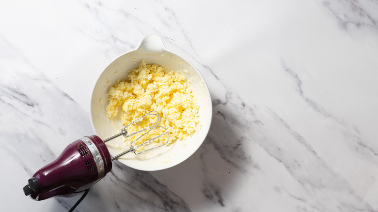 Bowl with butter and cheese and hand-held mixer