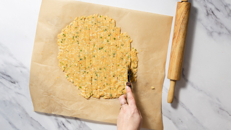 Rolled out cheese straws dough cut into strips