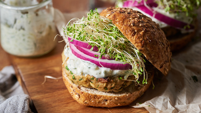 Tuna burgers topped with tzatziki, red onion, and alfalfa sprouts