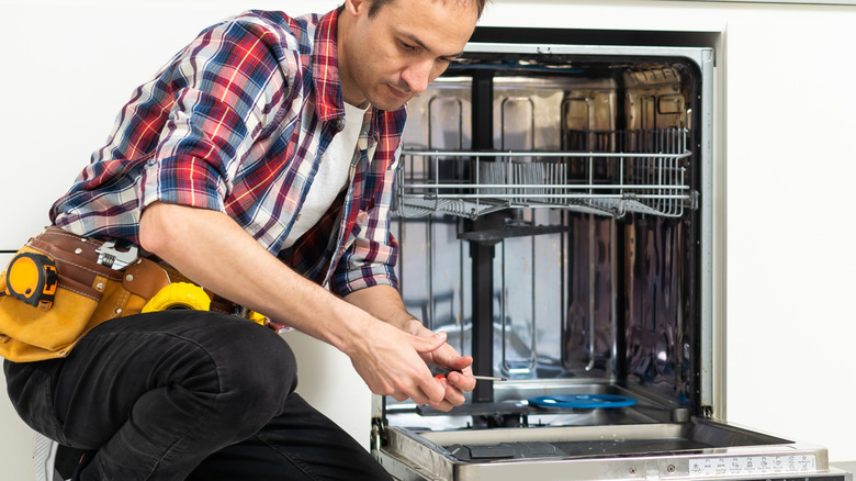 Worker repairing the dishwasher in kitchen